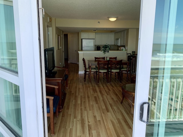 dining room with light wood-style flooring and a textured ceiling