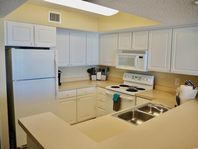 kitchen featuring white appliances, visible vents, white cabinets, light countertops, and a sink