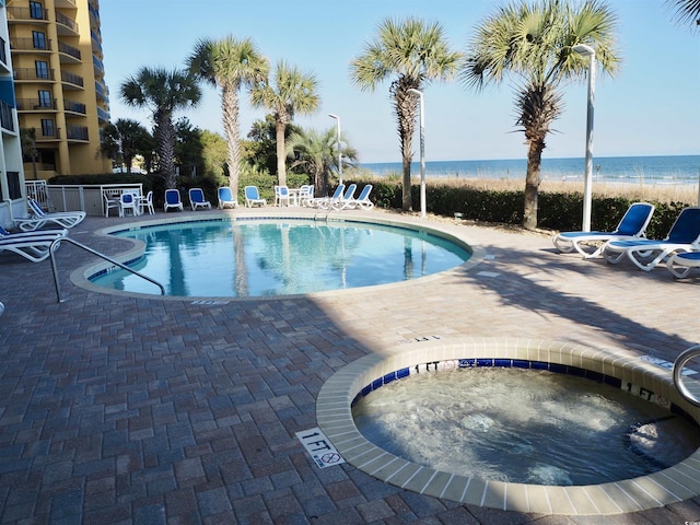 pool featuring a patio area, a community hot tub, and a water view