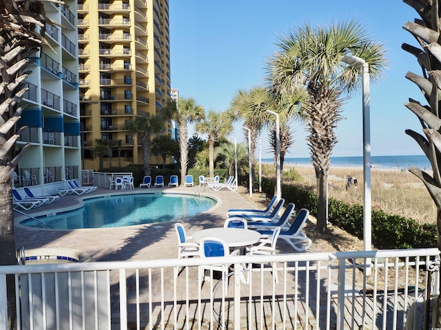 community pool with a water view, fence, and a patio