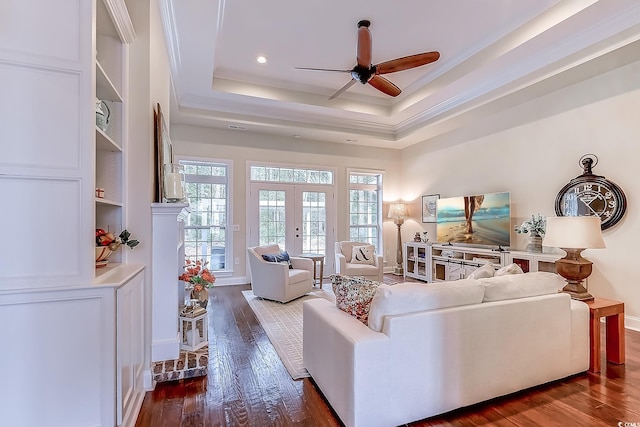 living room with ceiling fan, french doors, a raised ceiling, dark hardwood / wood-style flooring, and crown molding