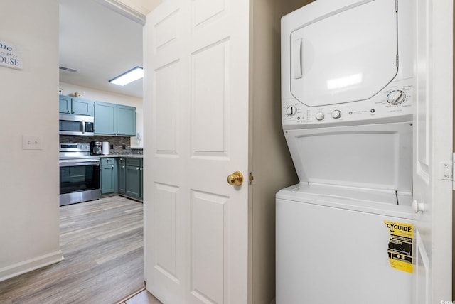 laundry room featuring stacked washer and clothes dryer and light wood-type flooring