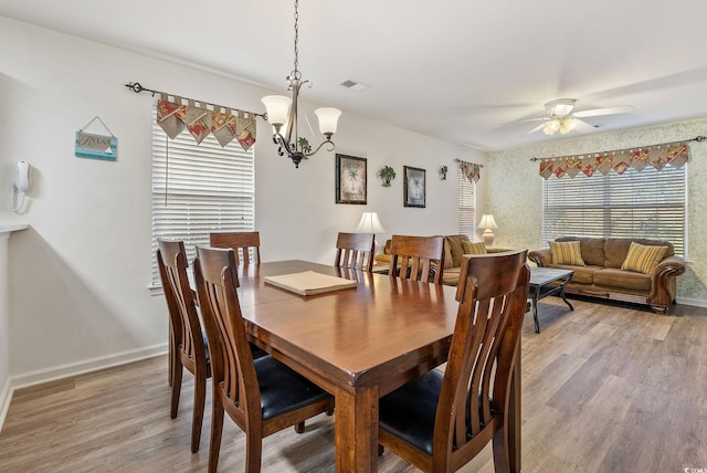 dining space with hardwood / wood-style floors and ceiling fan with notable chandelier