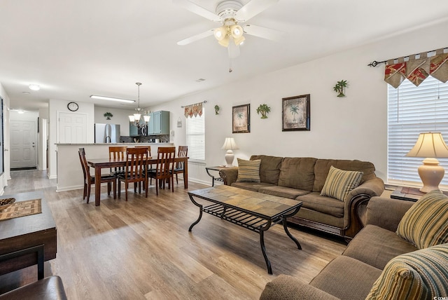 living room with ceiling fan with notable chandelier, light hardwood / wood-style floors, and a wealth of natural light