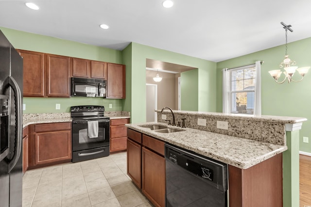 kitchen with sink, a notable chandelier, an island with sink, pendant lighting, and black appliances