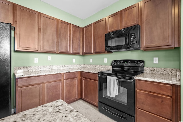 kitchen with black appliances, light tile patterned flooring, and light stone counters