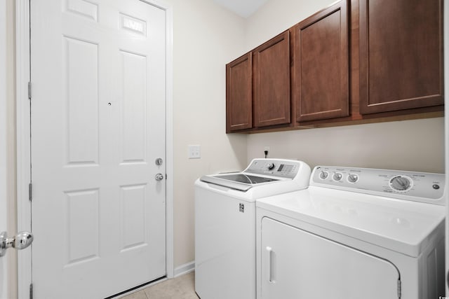 clothes washing area with cabinets, light tile patterned floors, and washing machine and dryer