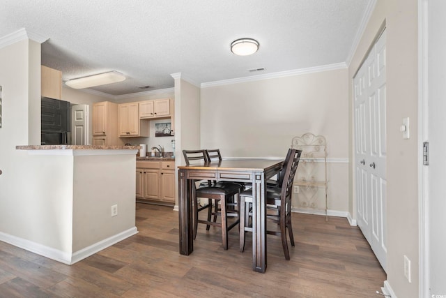 dining space featuring a textured ceiling, sink, ornamental molding, and dark wood-type flooring