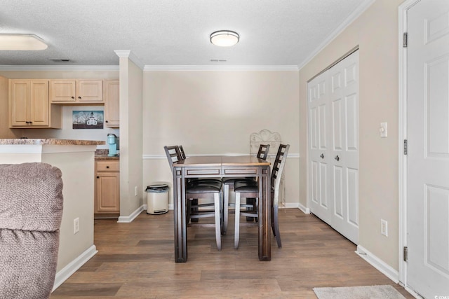 dining space with dark hardwood / wood-style flooring, a textured ceiling, and ornamental molding