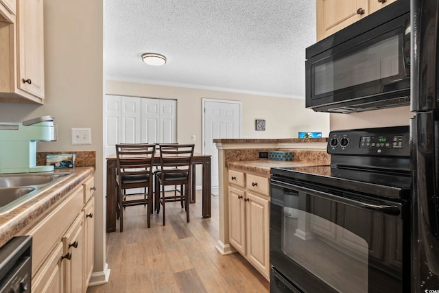 kitchen with a textured ceiling, light hardwood / wood-style flooring, ornamental molding, and black appliances