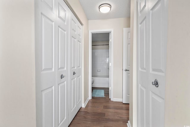 corridor with dark hardwood / wood-style flooring and a textured ceiling