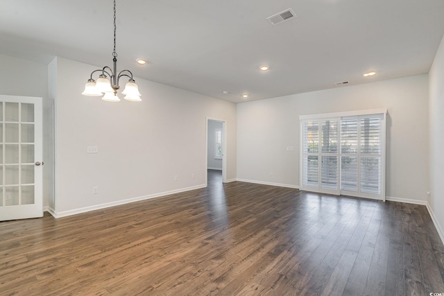 empty room featuring dark wood-type flooring and a chandelier