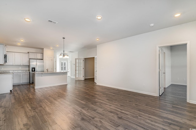 unfurnished living room featuring dark hardwood / wood-style flooring, sink, and a chandelier