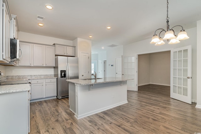 kitchen featuring stainless steel refrigerator with ice dispenser, sink, a center island with sink, a chandelier, and hanging light fixtures