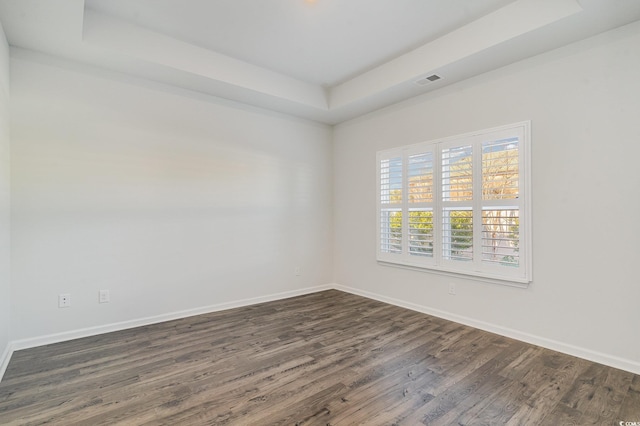 unfurnished room featuring dark hardwood / wood-style flooring and a tray ceiling