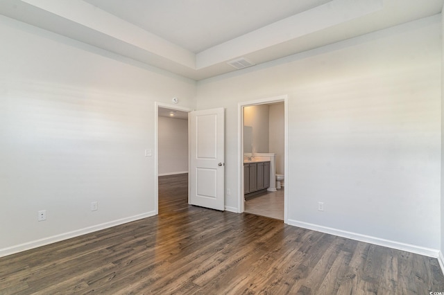 empty room with dark hardwood / wood-style flooring and a tray ceiling