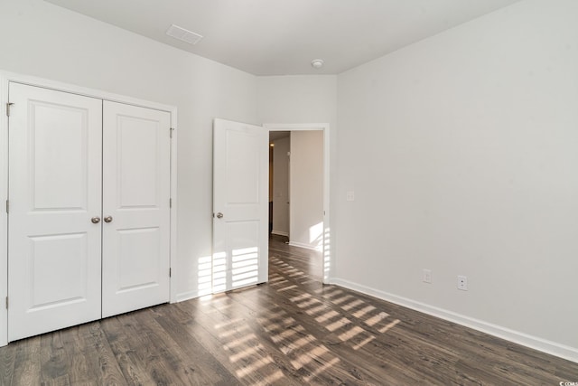 unfurnished bedroom featuring dark hardwood / wood-style flooring and a closet