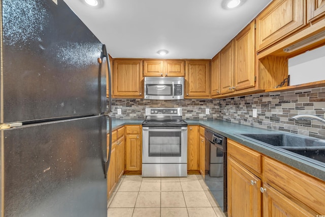 kitchen with sink, black appliances, tasteful backsplash, and light tile patterned flooring