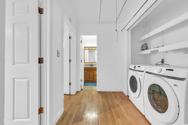 clothes washing area with sink, light wood-type flooring, and washer and dryer