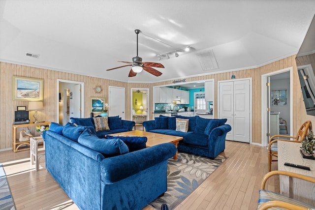 living room featuring ceiling fan, light wood-type flooring, rail lighting, and vaulted ceiling