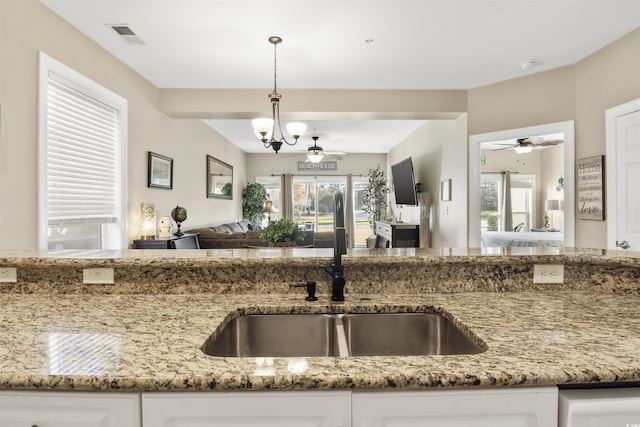 kitchen with white cabinetry, hanging light fixtures, light stone counters, and an inviting chandelier