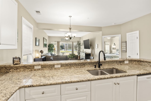 kitchen featuring pendant lighting, white dishwasher, sink, white cabinetry, and a chandelier