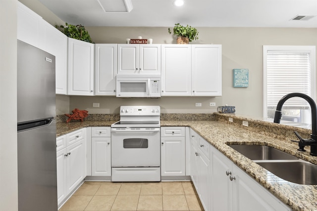 kitchen featuring stone counters, white cabinetry, sink, white appliances, and light tile patterned flooring