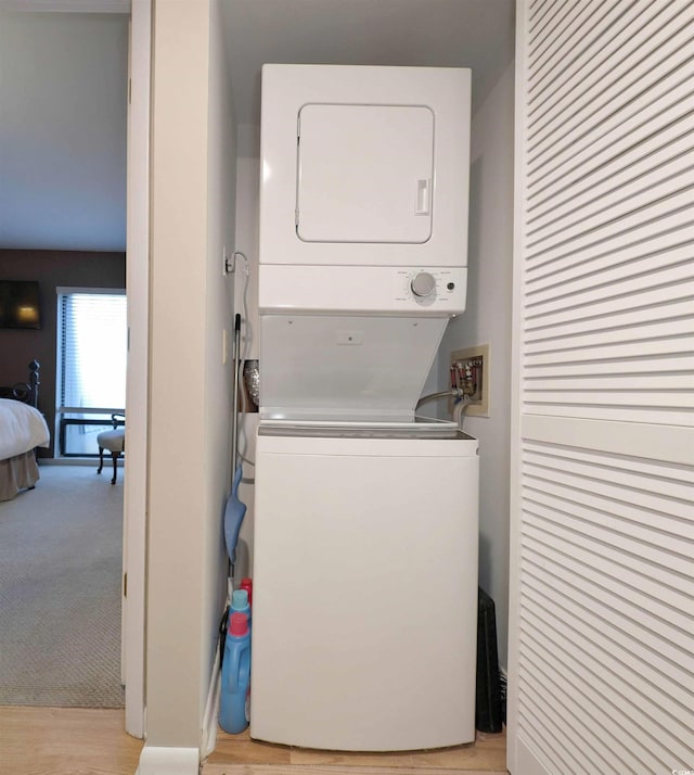 washroom featuring light colored carpet and stacked washer / dryer