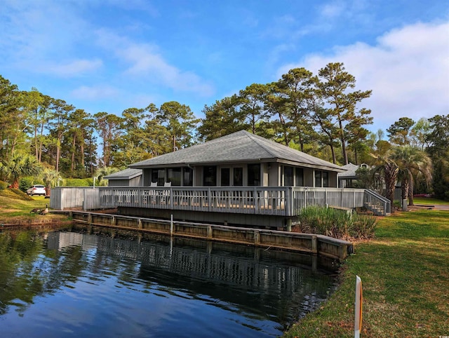 rear view of house with a sunroom, a water view, and a yard