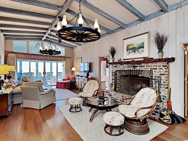 living room featuring wooden walls, a brick fireplace, vaulted ceiling with beams, wood-type flooring, and a chandelier