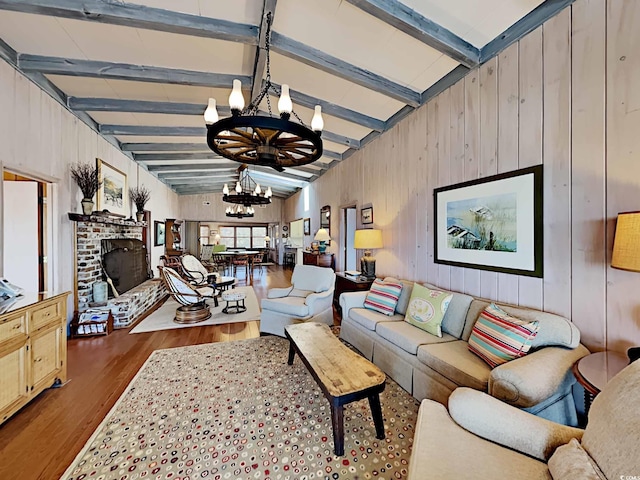 living room with lofted ceiling with beams, wood-type flooring, a fireplace, and an inviting chandelier