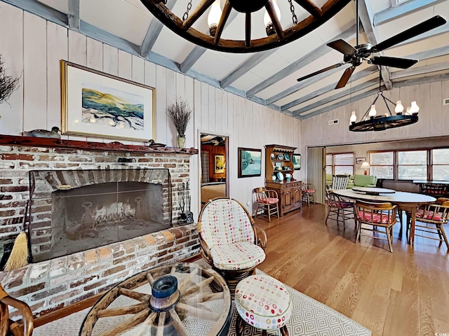 living room featuring lofted ceiling with beams, wood walls, a chandelier, light hardwood / wood-style floors, and a fireplace