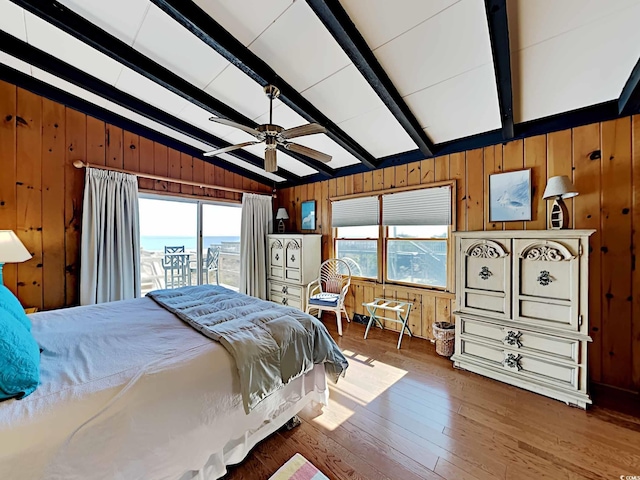 bedroom featuring access to outside, wooden walls, vaulted ceiling with beams, ceiling fan, and wood-type flooring