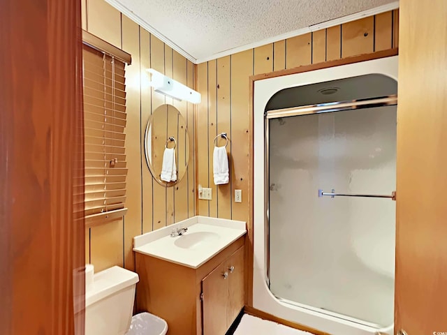 bathroom with ornamental molding, vanity, a textured ceiling, wooden walls, and toilet