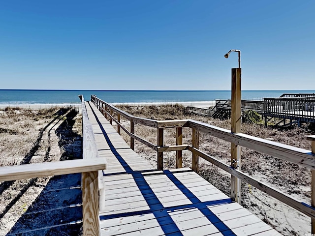 view of dock with a water view and a beach view