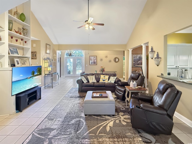 tiled living room with decorative columns, ceiling fan, french doors, and high vaulted ceiling