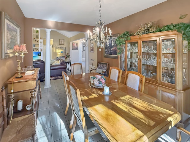 dining room with dark tile patterned flooring, ornate columns, and a notable chandelier