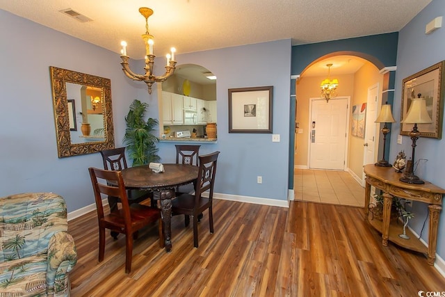 dining room with wood-type flooring, a textured ceiling, and a notable chandelier