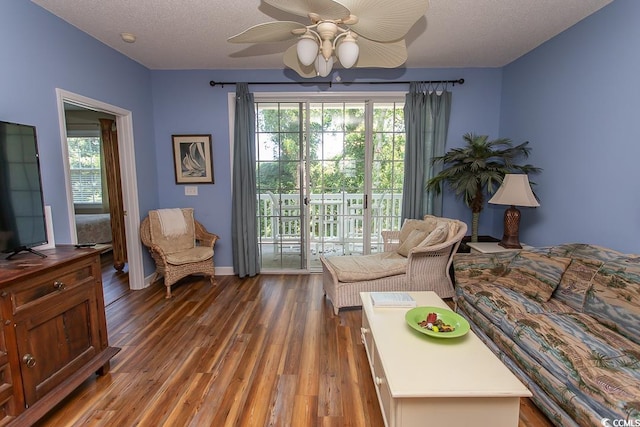 living room featuring ceiling fan, dark hardwood / wood-style flooring, and a textured ceiling