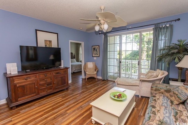 living room featuring ceiling fan, a textured ceiling, and dark wood-type flooring