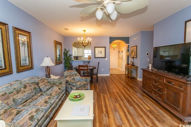 living room featuring hardwood / wood-style floors, ceiling fan with notable chandelier, and a textured ceiling