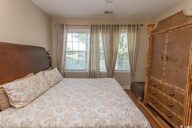 bedroom featuring multiple windows and dark hardwood / wood-style flooring