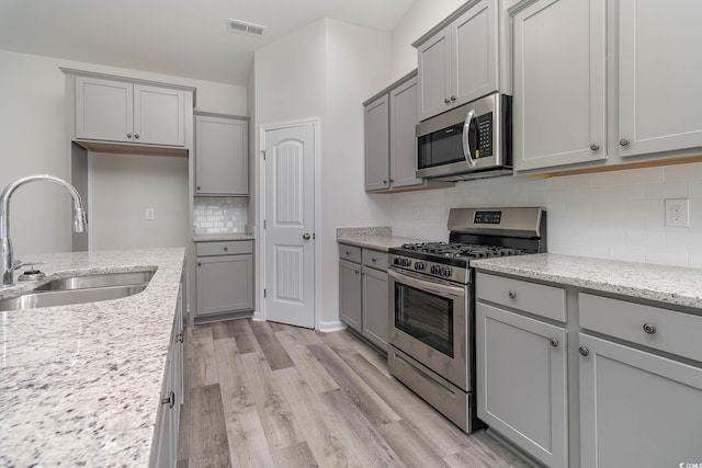 kitchen with gray cabinets, light stone countertops, sink, and appliances with stainless steel finishes