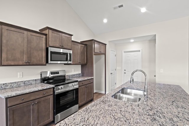 kitchen featuring light stone counters, dark brown cabinets, stainless steel appliances, sink, and hardwood / wood-style flooring