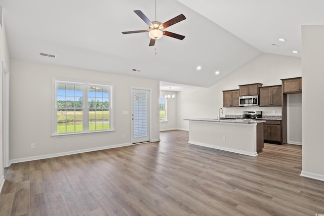 kitchen featuring an island with sink, light wood-type flooring, ceiling fan with notable chandelier, and appliances with stainless steel finishes