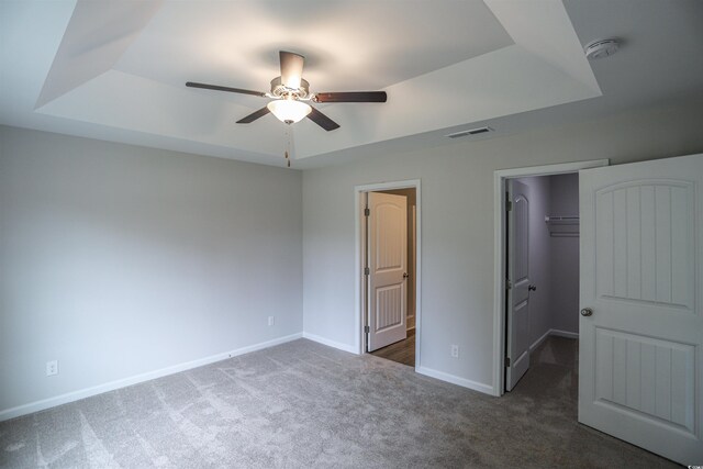399 Lifestyle Ct, Surfside Beach, SC 29575 - unfurnished bedroom with a walk in closet, dark carpet, a raised ceiling, ceiling fan, and a closet