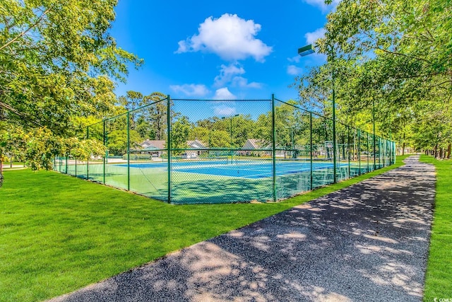 view of tennis court featuring a yard