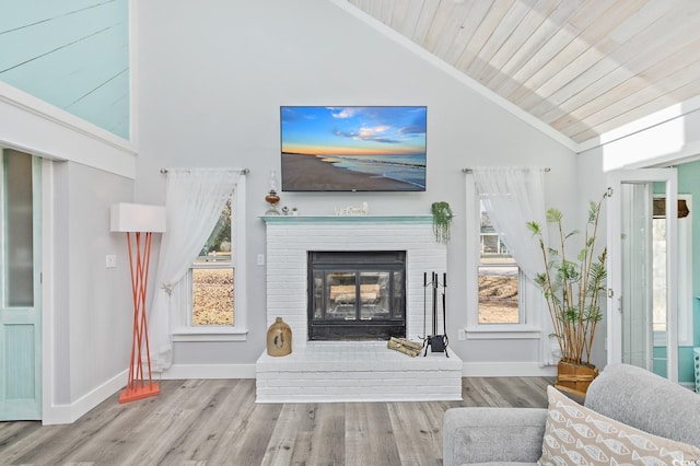 living room featuring high vaulted ceiling, crown molding, light hardwood / wood-style flooring, a brick fireplace, and wood ceiling