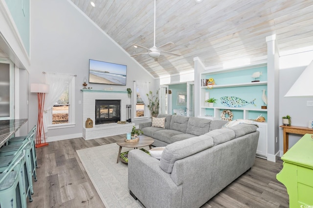 living room with a brick fireplace, wood ceiling, ceiling fan, wood-type flooring, and high vaulted ceiling