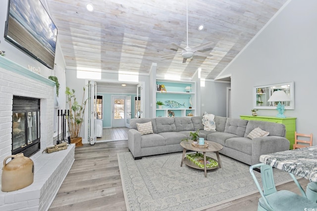 living room featuring ceiling fan, wood-type flooring, built in features, a fireplace, and lofted ceiling